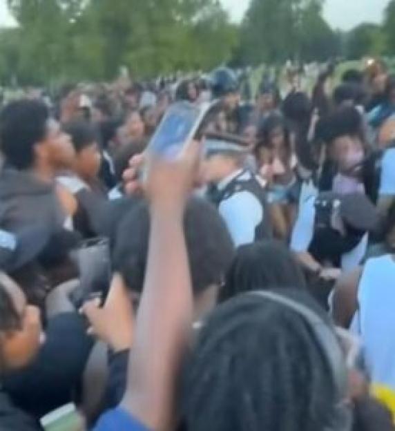 Police officer surrounded by a large crowd of people.