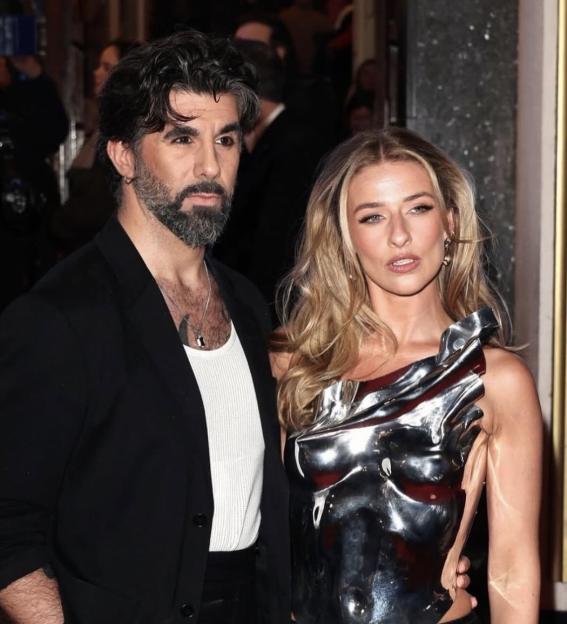 Man with beard and woman in metallic top posing together.