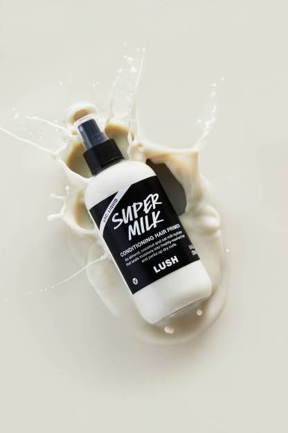Lush Super Milk conditioning hair primer bottle in milk splash.