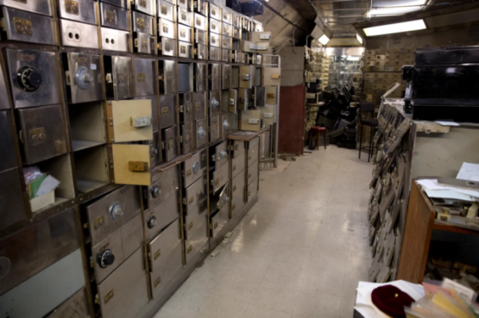 Vault with hundreds of open and closed safety deposit boxes, some with combination locks.