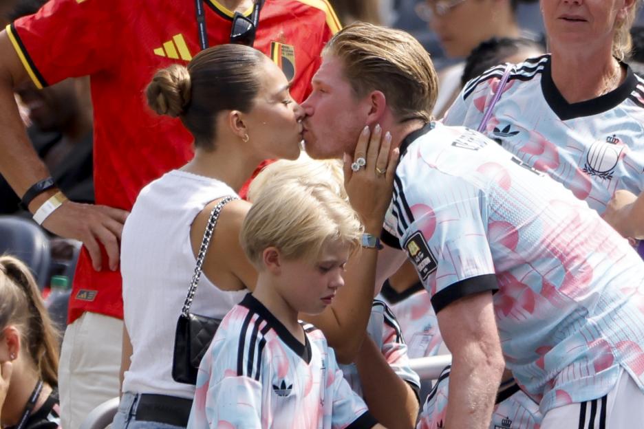 Kevin De Bruyne kissing his wife Michele De Bruyne with their son in the foreground.