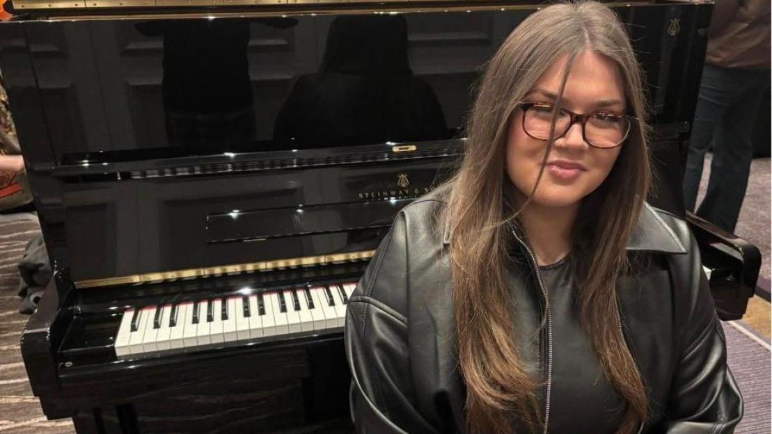 Grace Matthews posing next to a black Steinway & Sons piano.