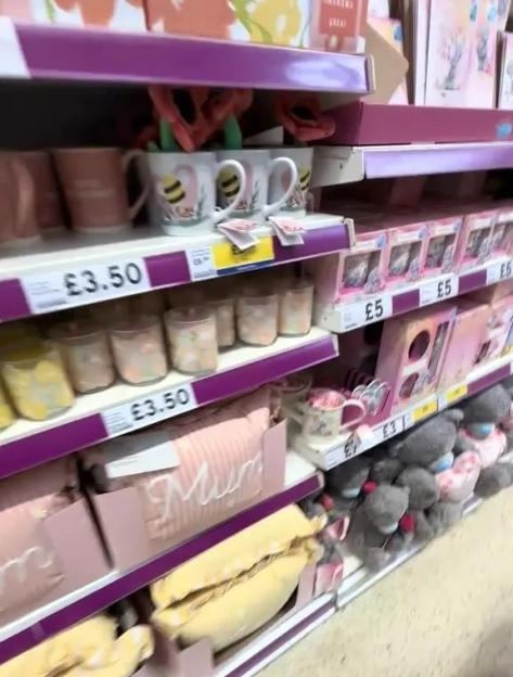 A supermarket aisle featuring various Mother's Day gifts such as mugs, candles, cushions, and stuffed animals.