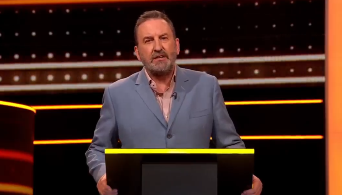 Comedian Bob Mortimer speaking at a podium.