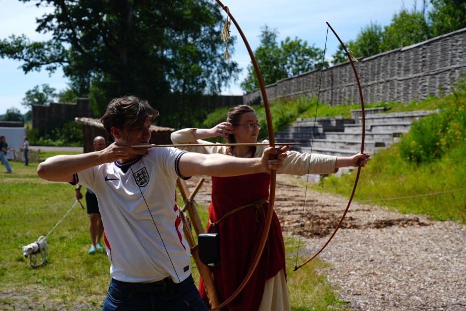 Ed Southgate receives an archery lesson from Ane Marie Hovda Angelsen.