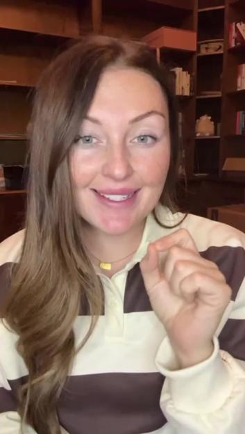 Chloe Smith, wearing a striped shirt, holding up her fingers as if measuring something small.