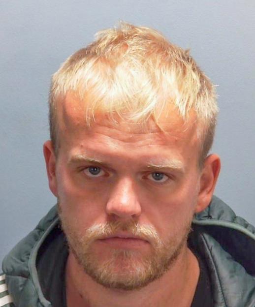 Mugshot of Charlie James Jeans, a man with fair hair and a beard, wearing a dark jacket.