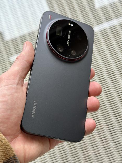A person's hand holding a Xiaomi phone, displaying its large circular camera module on the back.