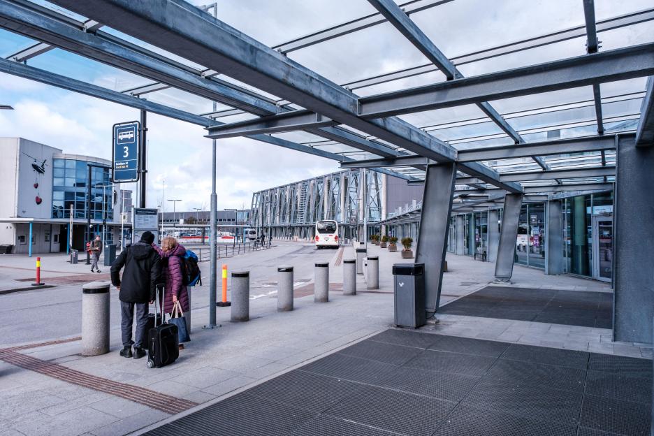 Two people waiting for a bus at Sola Airport Stavanger outside the main terminal building.