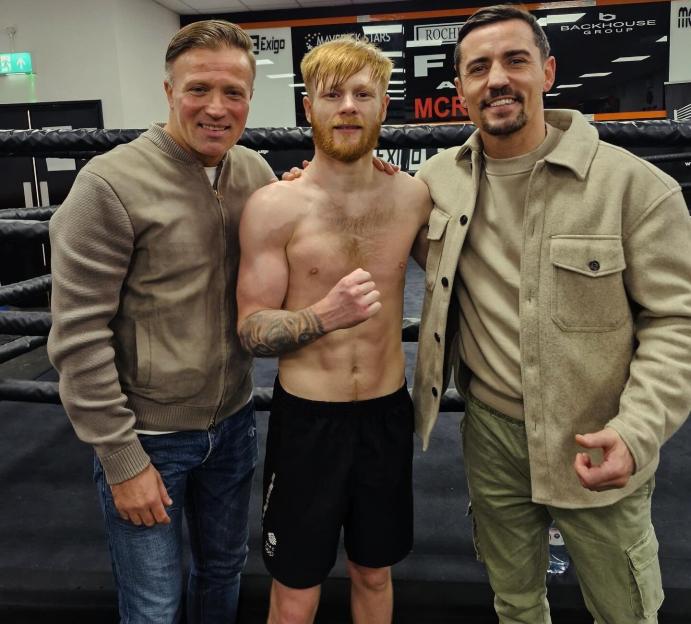 Three men posing in a boxing ring.
