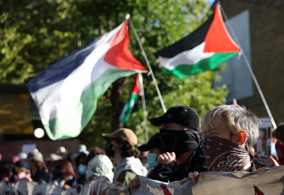 Demonstrators at an arms fair holding Palestinian flags and banners.