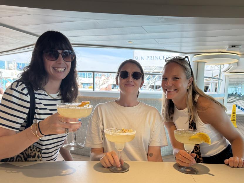 Three women smiling and holding margaritas on a Princess Cruise.