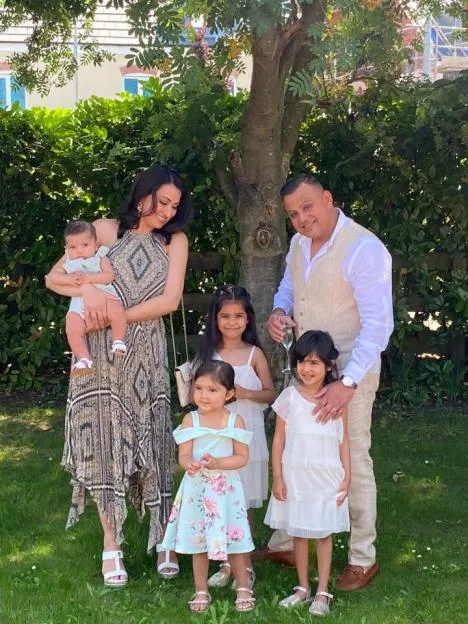 Jinda Mann and Bindu Mann pose outdoors with their family.
