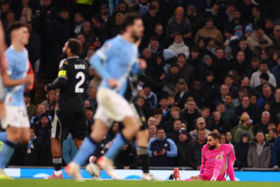 Leeds United goalkeeper Illan Meslier sits on the pitch after Manchester City scored a goal.