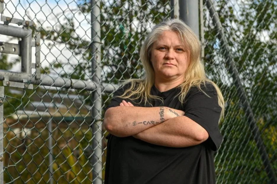 Sam Hammond standing with arms crossed in front of a chain-link fence.