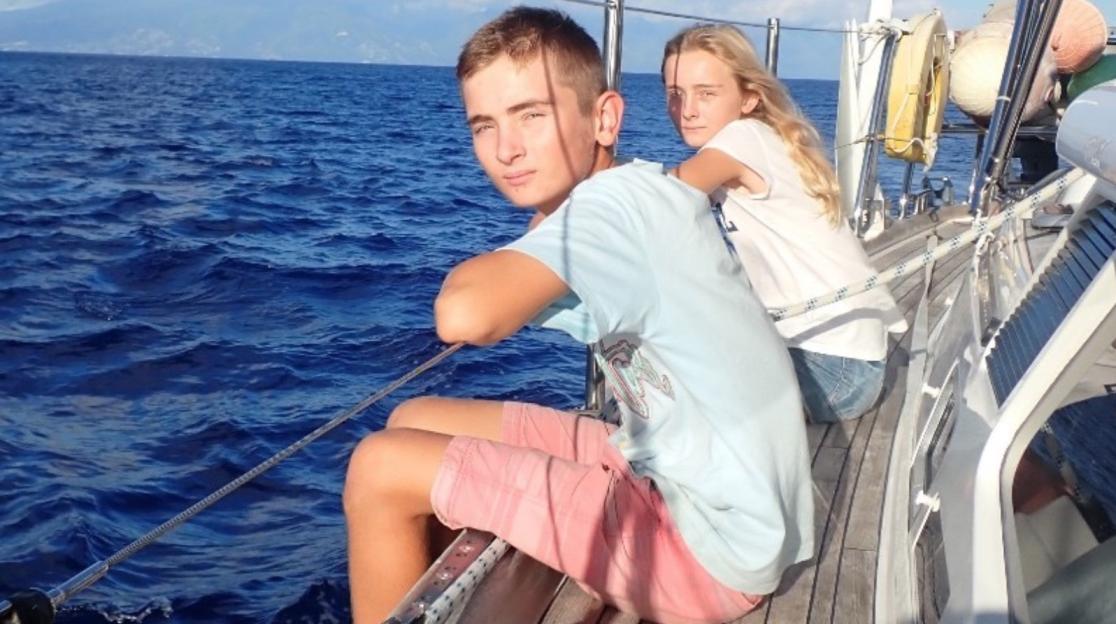 Teenage boy and girl sitting on a sailboat.