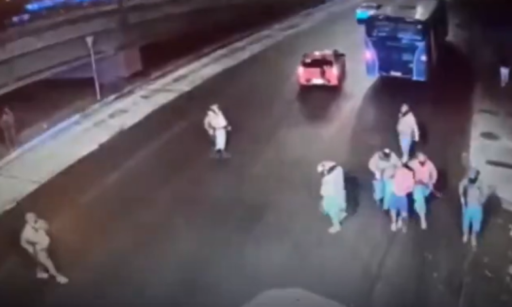 CCTV footage of people gathered on a street, with vehicles in the background.