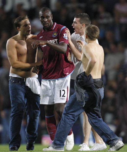 West Ham player Carlton Cole reacts to fans during a pitch invasion after a penalty goal.
