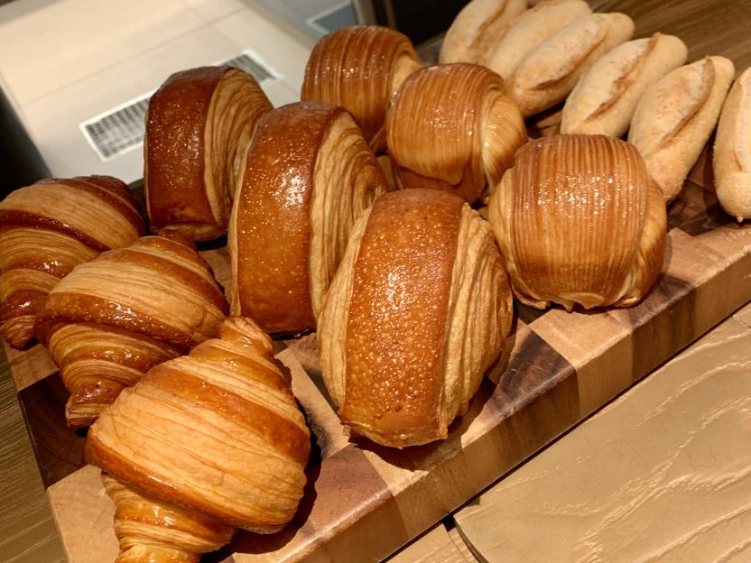 A wooden board filled with pastries, including croissants and pain au chocolat.