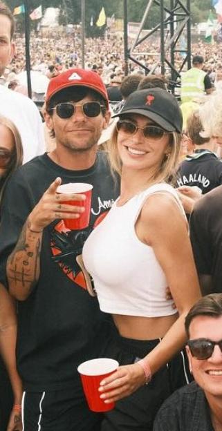 Louis Tomlinson and Zara McDermott pose with red cups at Glastonbury.