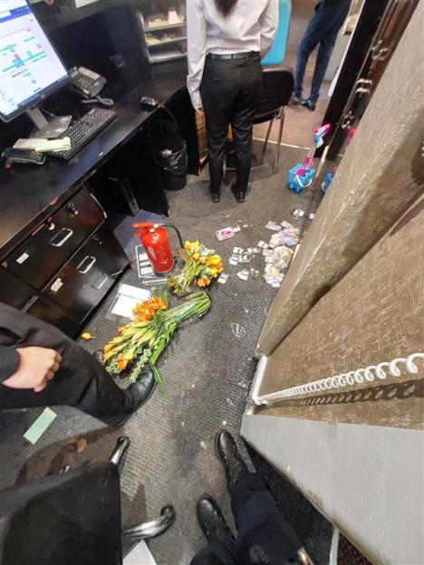 Damage to a hotel reception area, with flowers, a fire extinguisher, and debris scattered on the floor.