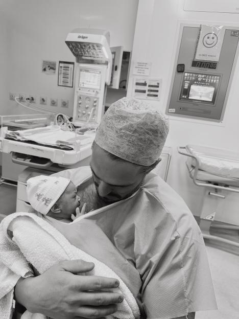 A man holding a newborn baby in a hospital room.