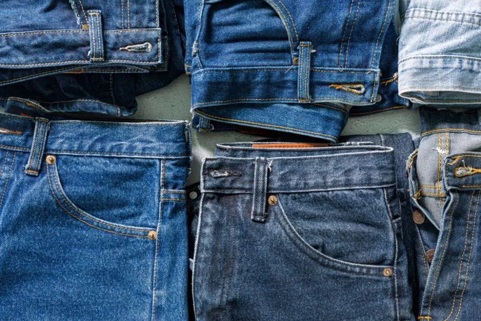 Top-down view of various folded denim jeans.