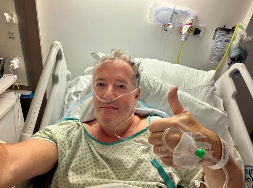 A man in a hospital bed with a nasal cannula gives a thumbs-up.