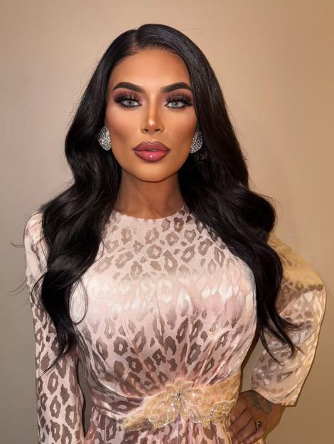 Drag Race star Baga Chipz posing in a pink leopard print dress.