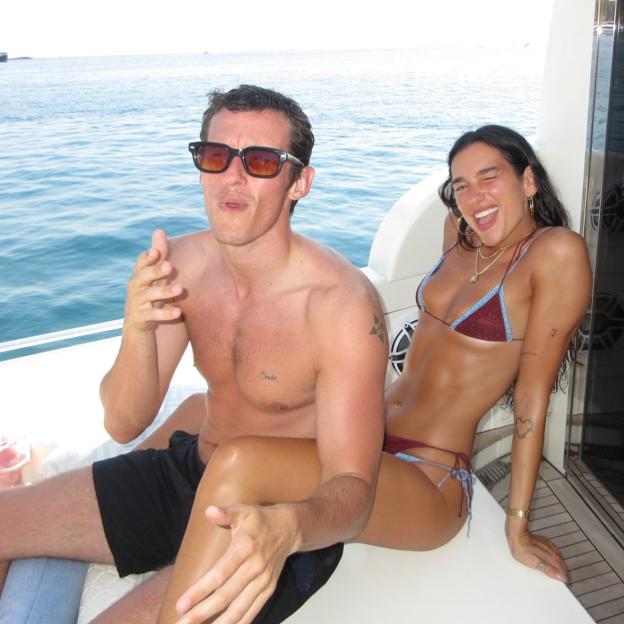 Dua Lipa and Callum Turner smiling on a boat.
