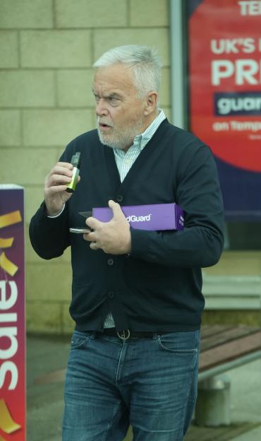 Huw Edwards outside a bed shop with a mattress cleaning kit and vape.
