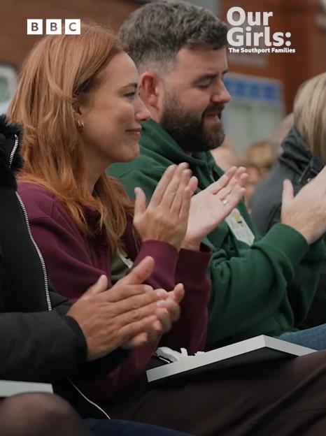 A crowd, including a red-haired woman and a bearded man, applauding. The text "Our Girls: The Southport Families" is at the top right, and "Tuesday 9th December, 8pm BBC ONE & iPLAYER" is at the bottom.