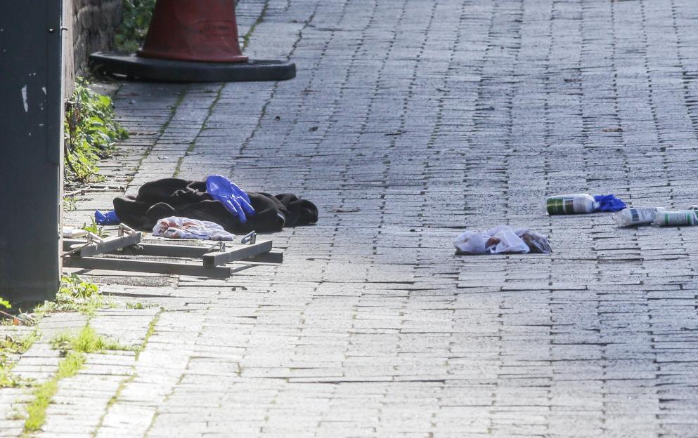 Blood-stained clothes, discarded medical gloves, and bottles on a brick path after a car ploughed into a crowd.