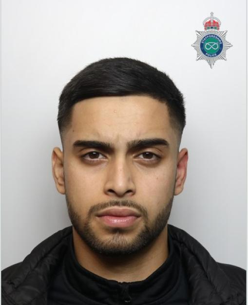 Mugshot of a young man with dark hair and a beard, wearing a black jacket, with the Staffordshire Police logo in the top right corner.