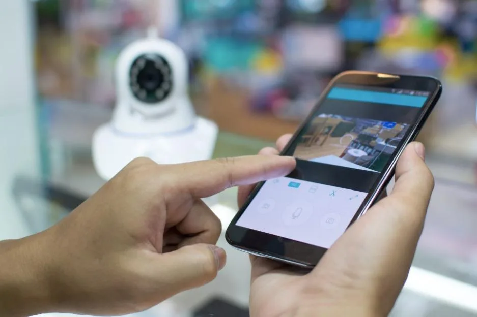 A hand using a smartphone app to control a home security camera.