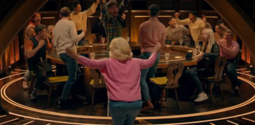 A group of excited people celebrate around a large circular table.