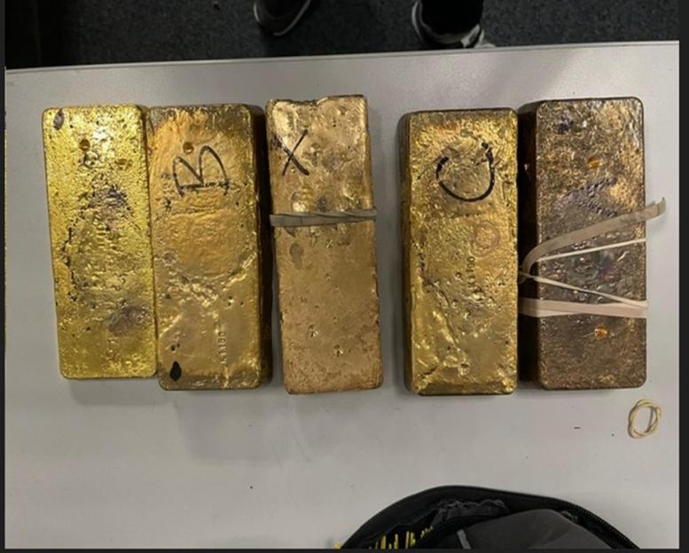 Five gold bars with markings on a table.