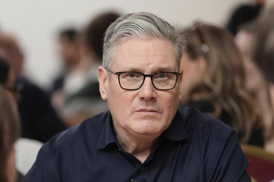 Keir Starmer, with gray hair and glasses, looking forward during a meeting with local party members.