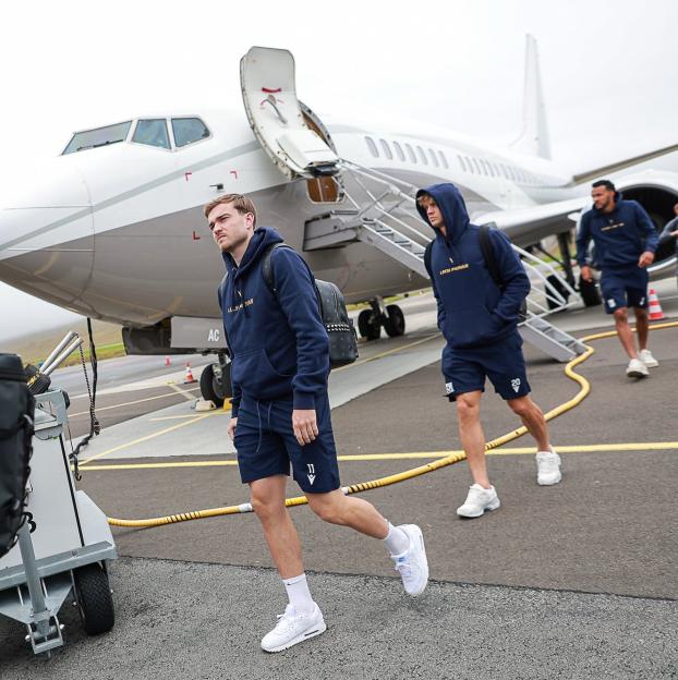 Football players walking from a private jet.
