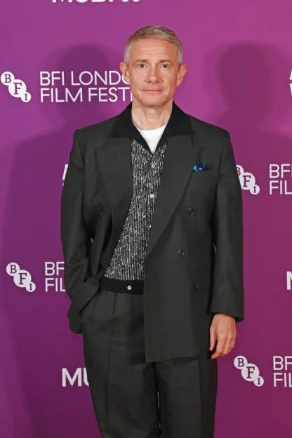 Martin Freeman poses in a dark suit and patterned shirt against a purple BFI London Film Festival backdrop.