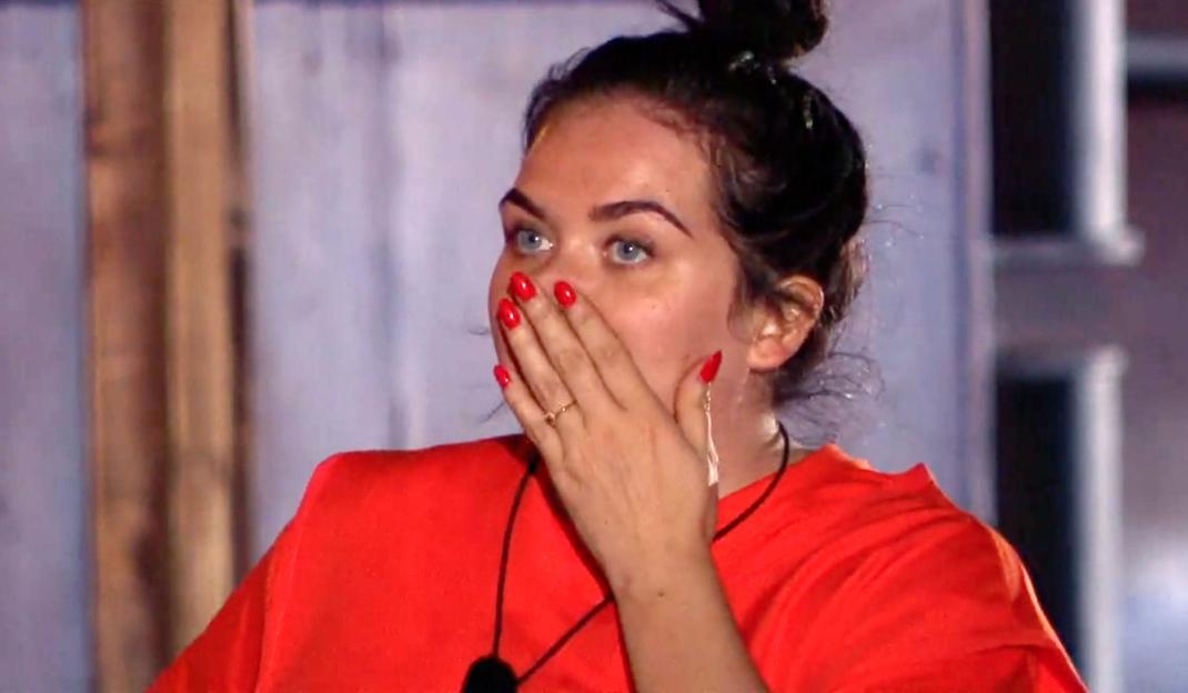 Scarlett Moffatt with her hand over her mouth, wearing a red shirt.