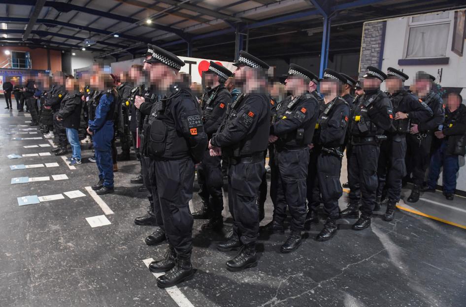 Greater Manchester Police officers, some wearing tactical vests, stand in a line during a briefing for Operation Copenhagen.