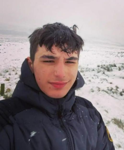 Kalen, a young man, in a dark blue puffer jacket, in a snowy landscape.