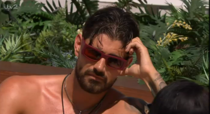 A man with red sunglasses and a hand on his head, looking troubled.