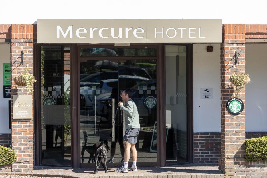 Man with a dog on a leash exiting the Mercure Hotel.