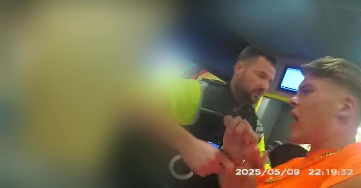 A police officer arresting Sonny Boyes, who is wearing an orange shirt and gold chain.