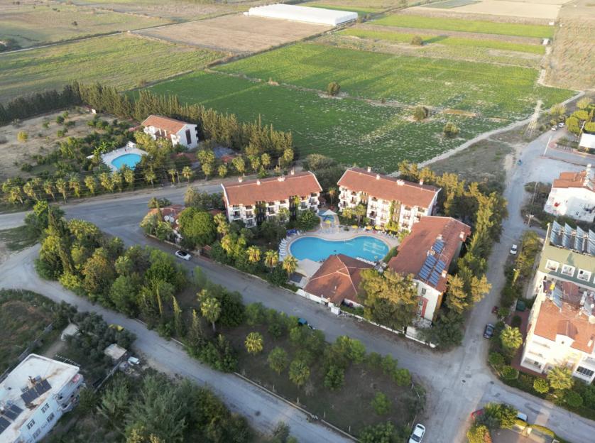 Aerial view of Lemas Suites Hotel Side with pools, surrounding buildings, and farmland.