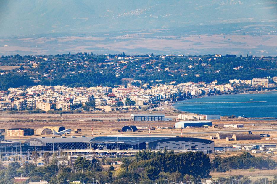 Aerial view of Thessaloniki Airport, a plane on the runway, and coastal suburbs along the Thermaic Gulf, Greece.