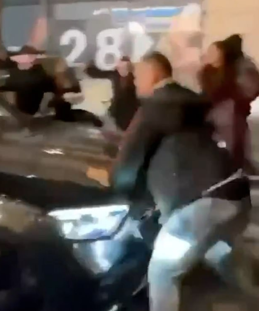 People fighting around a vehicle.