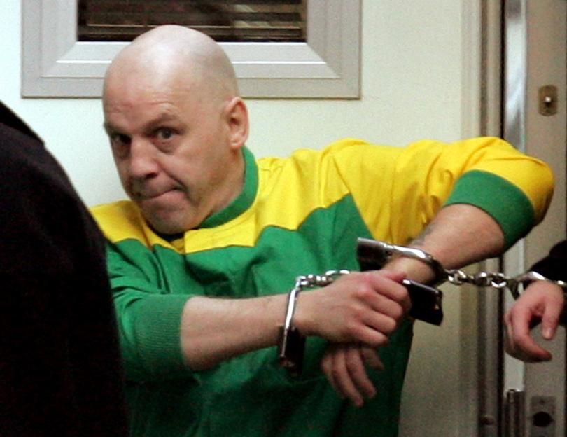 Michael Stone in handcuffs, wearing a green and yellow shirt.